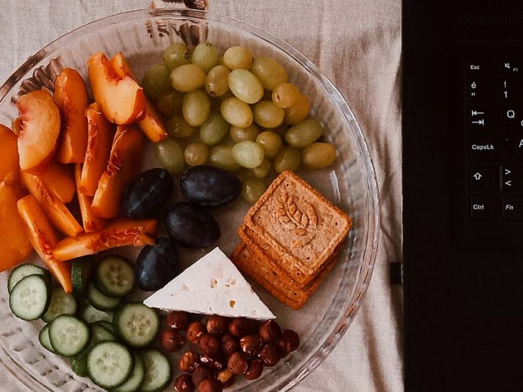 A delightful snack plate with fruits, cheese, and a laptop for a healthy lifestyle.